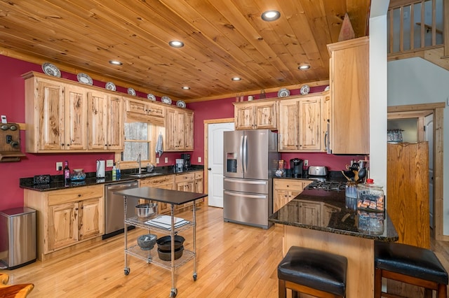 kitchen featuring light wood finished floors, stainless steel appliances, wood ceiling, a sink, and a peninsula