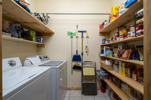 clothes washing area featuring laundry area, washer and clothes dryer, baseboards, and light tile patterned floors