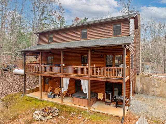 rear view of property with a deck, a fire pit, a shingled roof, a chimney, and a patio area