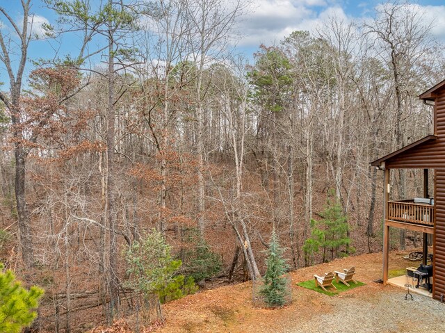 view of yard with a wooden deck and a forest view