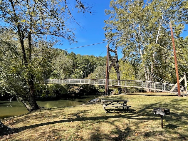 view of community featuring a water view, a wooded view, and a yard