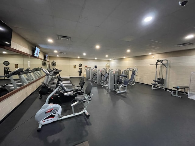 exercise room with recessed lighting, visible vents, and concrete block wall