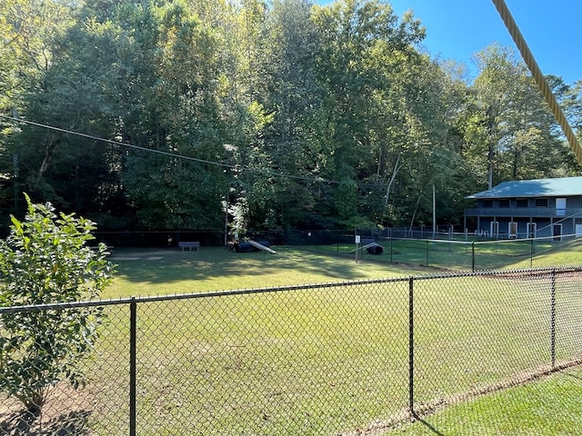 view of tennis court featuring fence and a yard