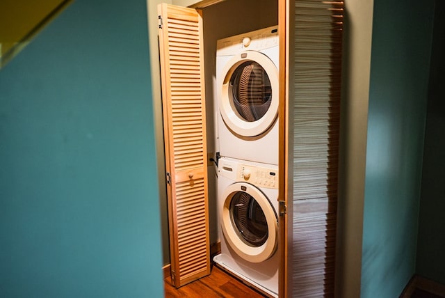 laundry room featuring stacked washing maching and dryer and hardwood / wood-style flooring