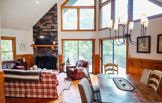 living room with a chandelier, wood-type flooring, a stone fireplace, and a wealth of natural light