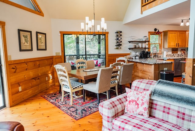 dining area featuring light wood-type flooring, lofted ceiling, sink, and a chandelier