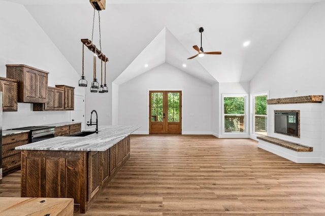 109 Lakeview Ct, Ellijay, GA 30540 - kitchen featuring open floor plan, a ceiling fan, a glass covered fireplace, a kitchen island with sink, and high vaulted ceiling