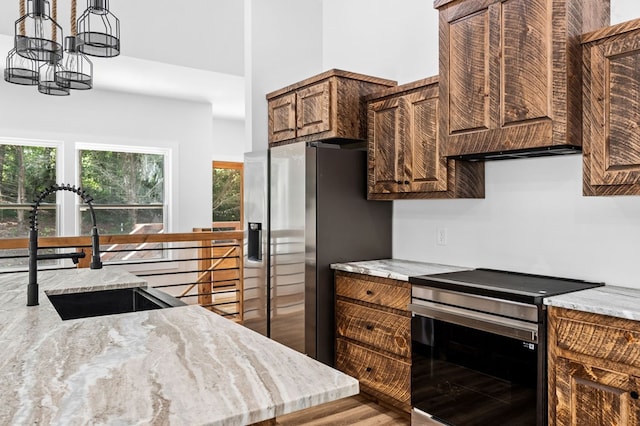 109 Lakeview Ct, Ellijay, GA 30540 - kitchen featuring stainless steel appliances, wood finished floors, light stone counters, a chandelier, and a towering ceiling