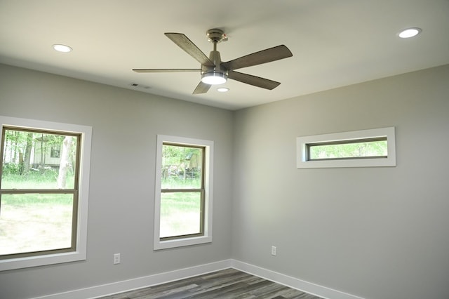 empty room featuring a wealth of natural light, ceiling fan, and dark wood-type flooring