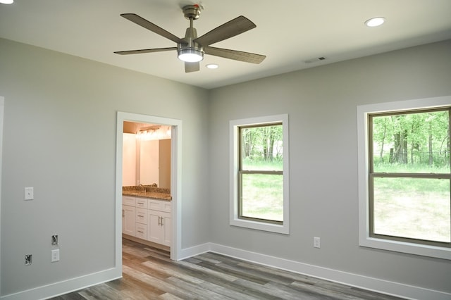 unfurnished bedroom with hardwood / wood-style flooring, ensuite bath, and ceiling fan