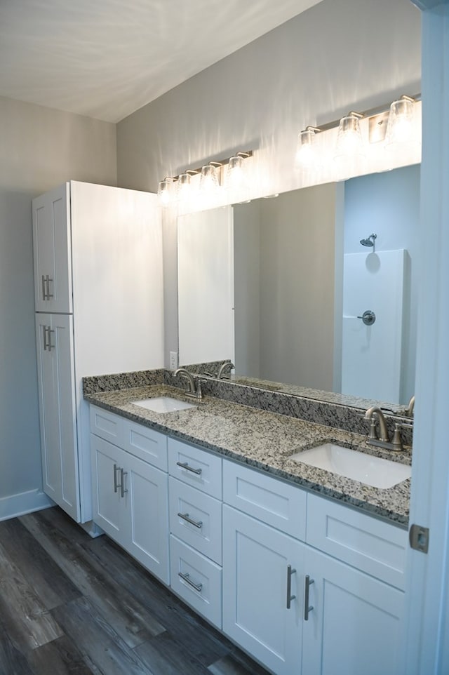 bathroom with dual sinks, vanity with extensive cabinet space, and hardwood / wood-style flooring