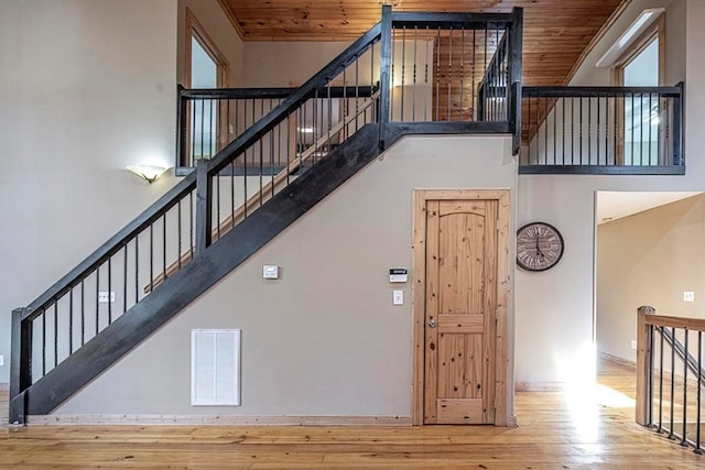 stairs with hardwood / wood-style flooring, wooden ceiling, and a high ceiling