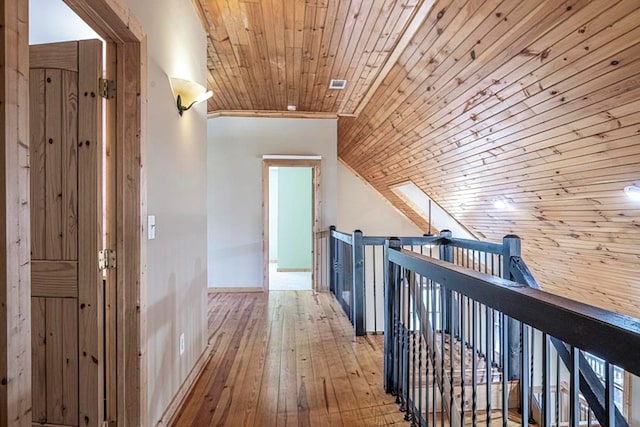 hallway with lofted ceiling, light hardwood / wood-style floors, and wooden ceiling