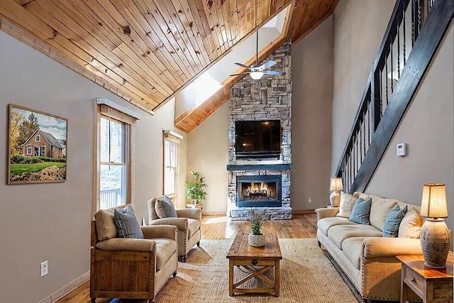 living room featuring a stone fireplace, high vaulted ceiling, wood-type flooring, ceiling fan, and wood ceiling