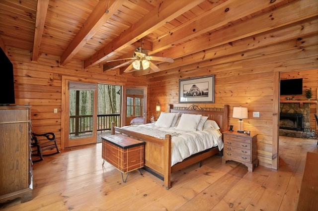 bedroom with beam ceiling, access to outside, a fireplace, and light wood finished floors