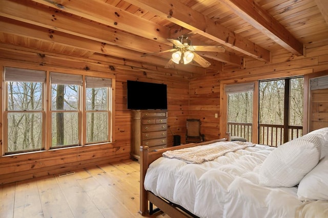 bedroom featuring beam ceiling, multiple windows, light wood-style flooring, and access to outside