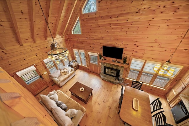 living area featuring beamed ceiling, wood walls, wood ceiling, a fireplace, and hardwood / wood-style flooring