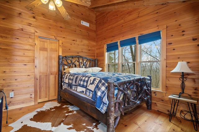 bedroom featuring wooden walls, visible vents, and wood-type flooring