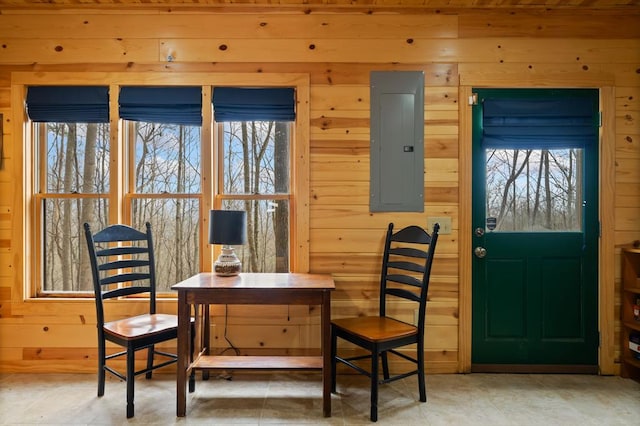 dining space with electric panel, wooden walls, and a wealth of natural light