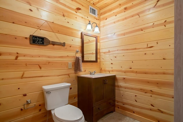 bathroom with visible vents, toilet, wood walls, and vanity