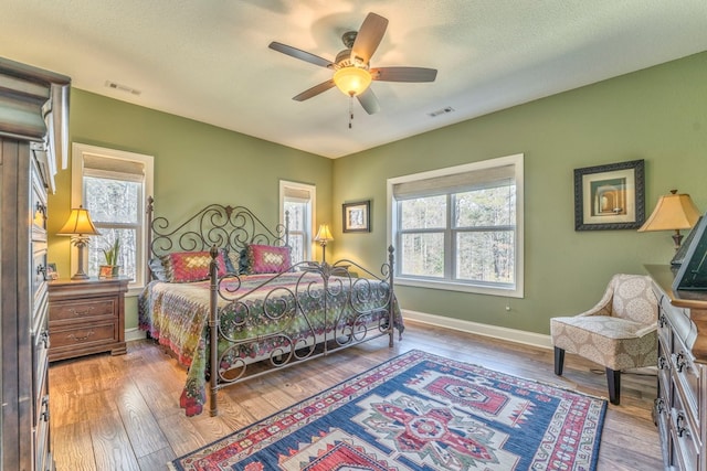 bedroom featuring a textured ceiling, light wood finished floors, visible vents, and baseboards