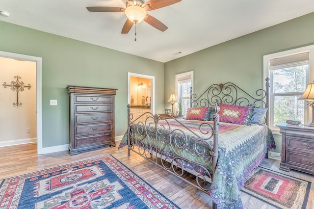 bedroom with multiple windows, baseboards, and wood finished floors