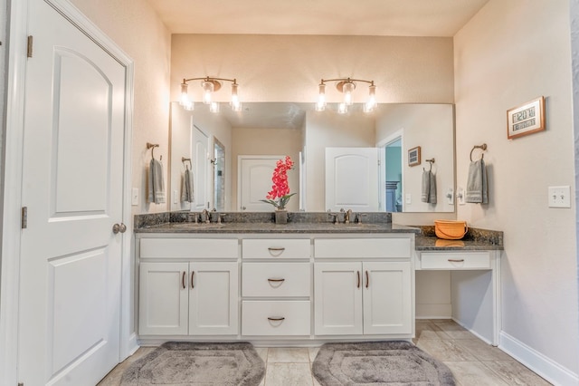 bathroom featuring double vanity, a sink, and baseboards