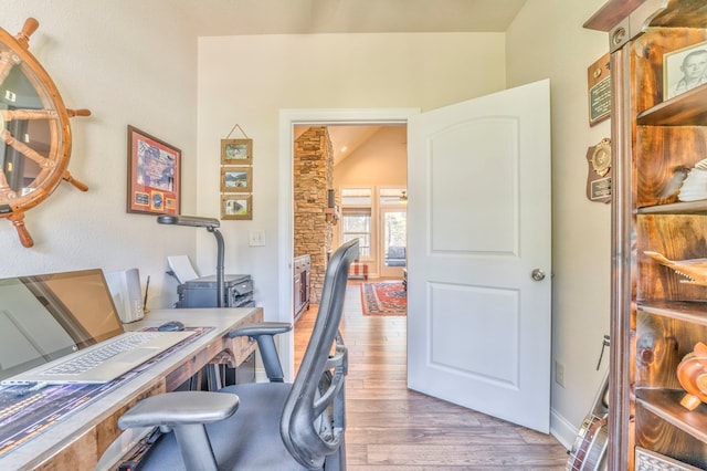 office with vaulted ceiling and light wood-style flooring