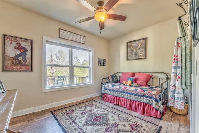 bedroom featuring a ceiling fan, visible vents, baseboards, and wood finished floors