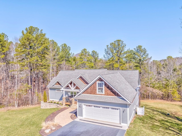 craftsman-style house with a garage, aphalt driveway, a front lawn, and a view of trees