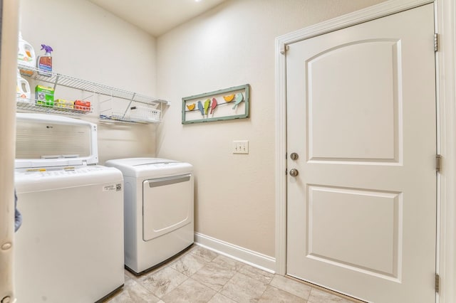 washroom featuring laundry area, baseboards, and separate washer and dryer