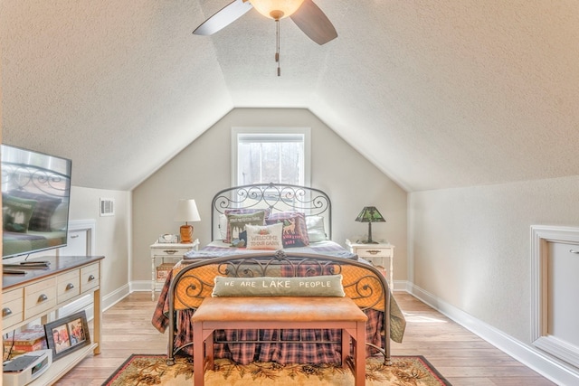 bedroom with a ceiling fan, vaulted ceiling, light wood-style flooring, and a textured ceiling