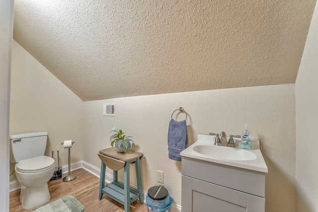 bathroom with lofted ceiling, visible vents, toilet, wood finished floors, and baseboards