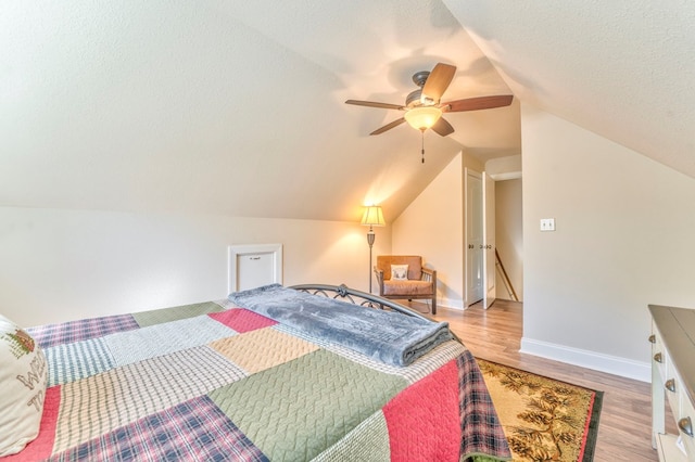 bedroom with a textured ceiling, a ceiling fan, baseboards, vaulted ceiling, and light wood-type flooring