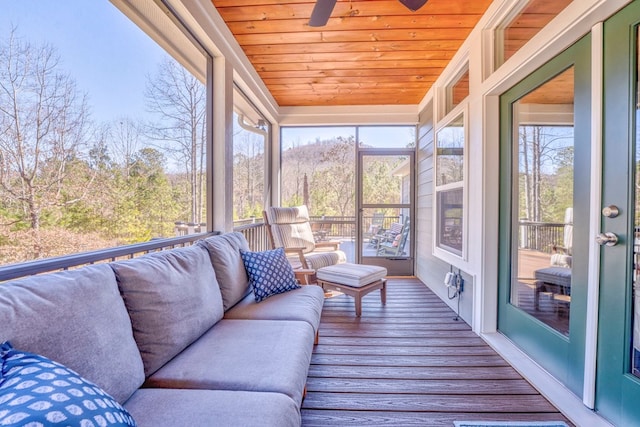 sunroom featuring a ceiling fan, wooden ceiling, and a healthy amount of sunlight