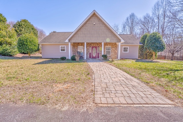 view of front of property featuring covered porch, stone siding, and a front lawn