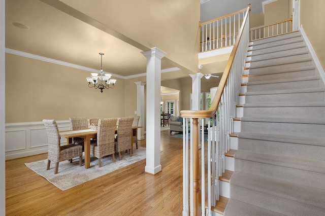 dining space with stairway, light wood-style flooring, decorative columns, and crown molding