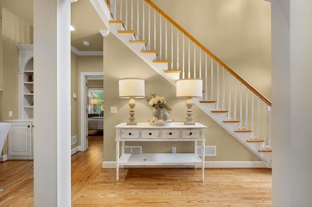 stairway featuring visible vents, ornamental molding, wood finished floors, a high ceiling, and baseboards