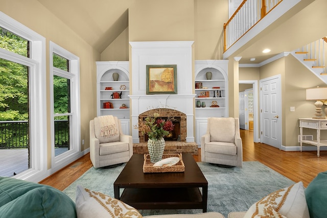 living area featuring a towering ceiling, baseboards, wood finished floors, and a fireplace