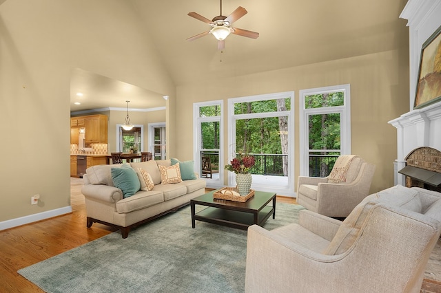 living room featuring high vaulted ceiling, ornamental molding, wood finished floors, baseboards, and a brick fireplace