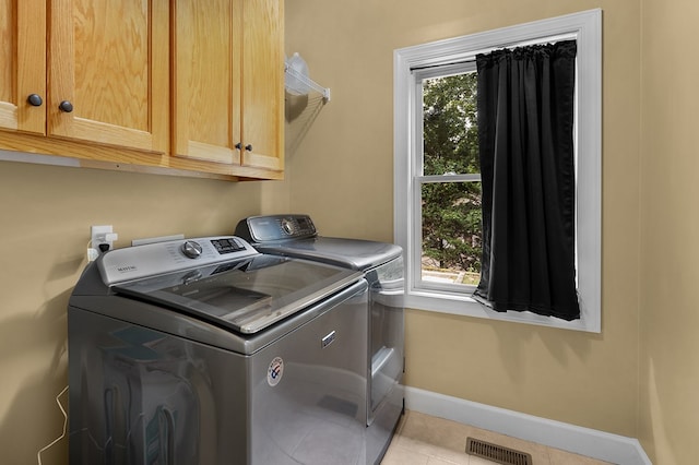 washroom with washing machine and clothes dryer, visible vents, tile patterned flooring, baseboards, and cabinet space