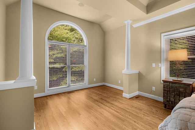 bedroom with decorative columns, baseboards, and wood finished floors