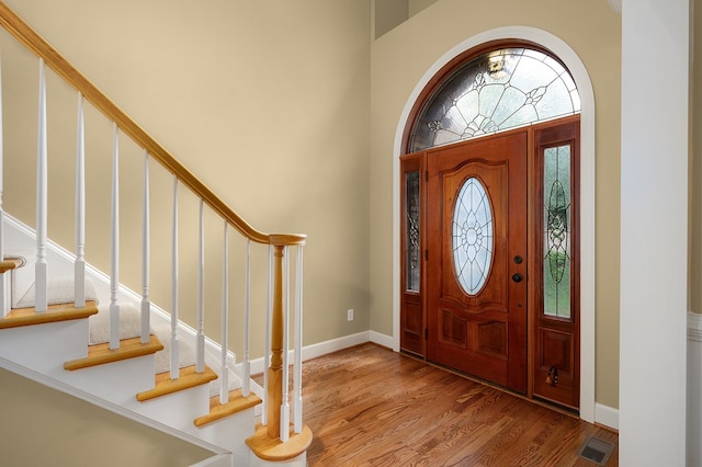 entrance foyer with visible vents, a high ceiling, baseboards, and wood finished floors