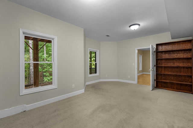 spare room featuring visible vents, light colored carpet, and baseboards