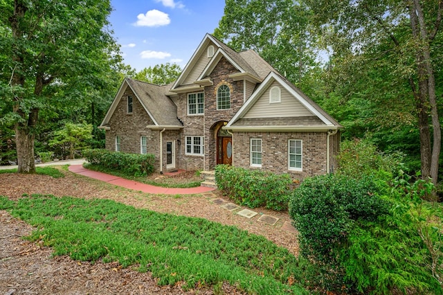 craftsman inspired home with stone siding, brick siding, and a shingled roof