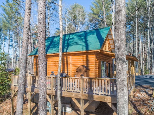 view of side of home featuring metal roof, log veneer siding, and a wooden deck