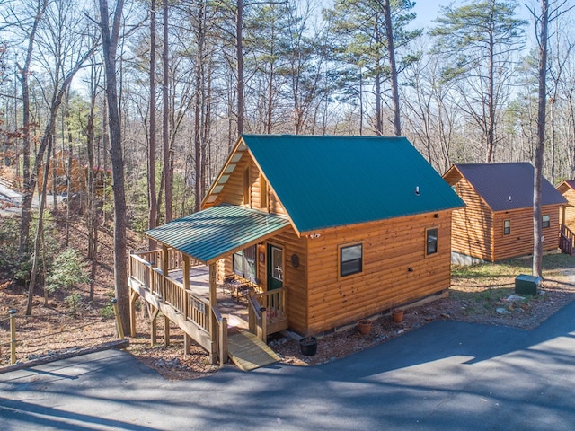 view of front facade with metal roof, a porch, faux log siding, and aphalt driveway
