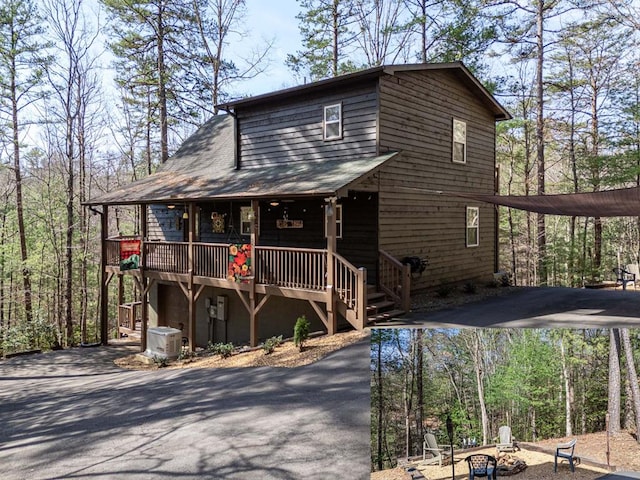 chalet / cabin with driveway, covered porch, a fire pit, and cooling unit