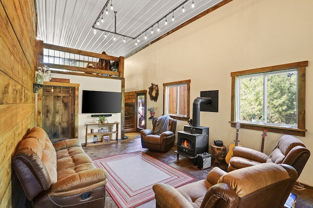 living room featuring a high ceiling, a wood stove, and concrete floors