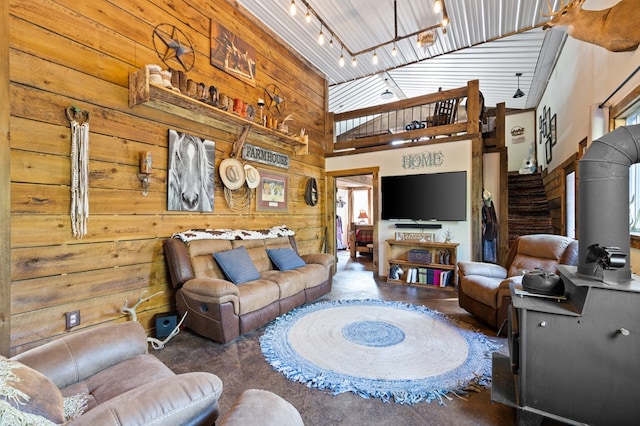 living room featuring track lighting, a high ceiling, and wood walls